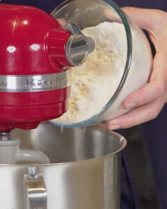 Hogaza de pan blanco con masa madre recién horneada junto a un bote de masa madre activa