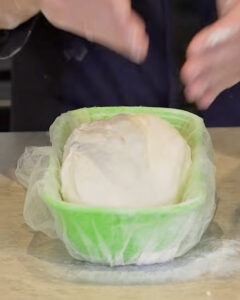 Hogaza de pan blanco con masa madre recién horneada junto a un bote de masa madre activa