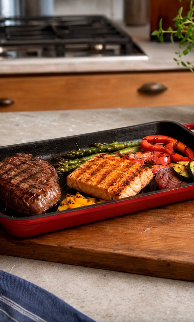Verduras, carne y pescado cocinados en grill asador de acero inoxidable con marcas de parrilla