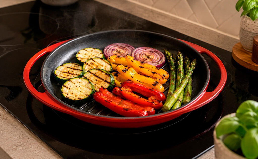 Verduras, carne y pescado cocinados en grill asador de acero inoxidable con marcas de parrilla