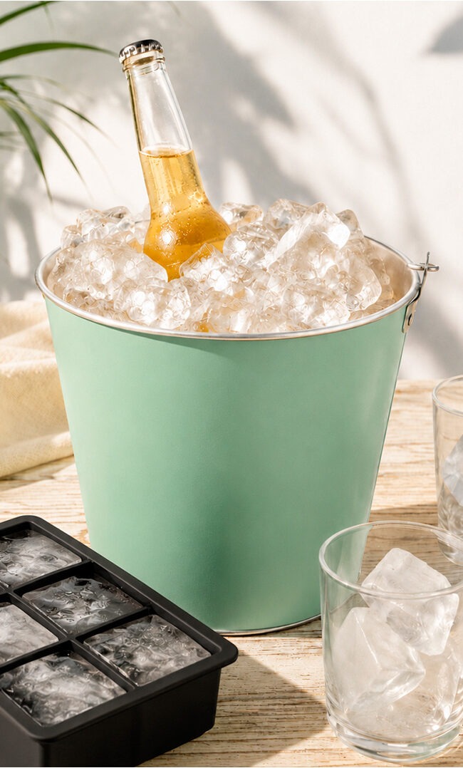 Cubitera para hielo de acero inoxidable Koala y cubitera de silicona XXL con cubitos grandes sobre mesa de verano