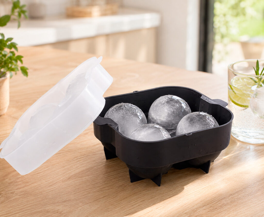 Cubitera para hielo de acero inoxidable Koala y cubitera de silicona XXL con cubitos grandes sobre mesa de verano