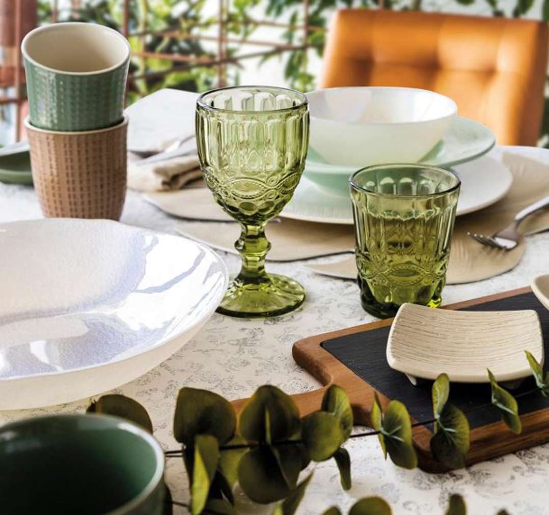 Una mesa impecablemente dispuesta con vajilla y copas elegantes.