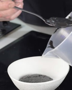 Arroz meloso de choco con mayonesa de tinta negra servido en plato hondo blanco