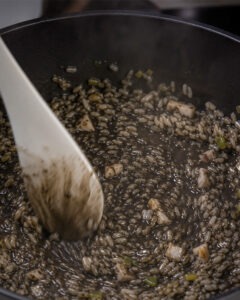 Arroz meloso de choco con mayonesa de tinta negra servido en plato hondo blanco