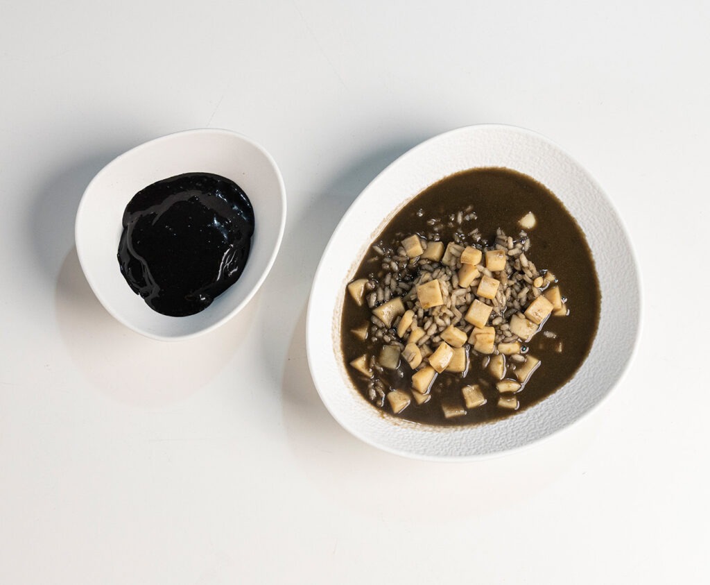 Arroz meloso de choco con mayonesa de tinta negra servido en plato hondo blanco