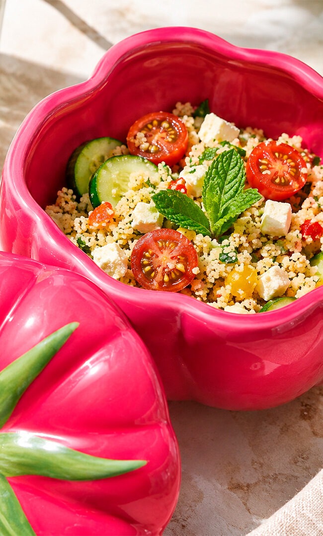 Bol de tabulé de cous cous con queso feta, tomates cherry, pepino y hierbabuena fresca sobre mármol
