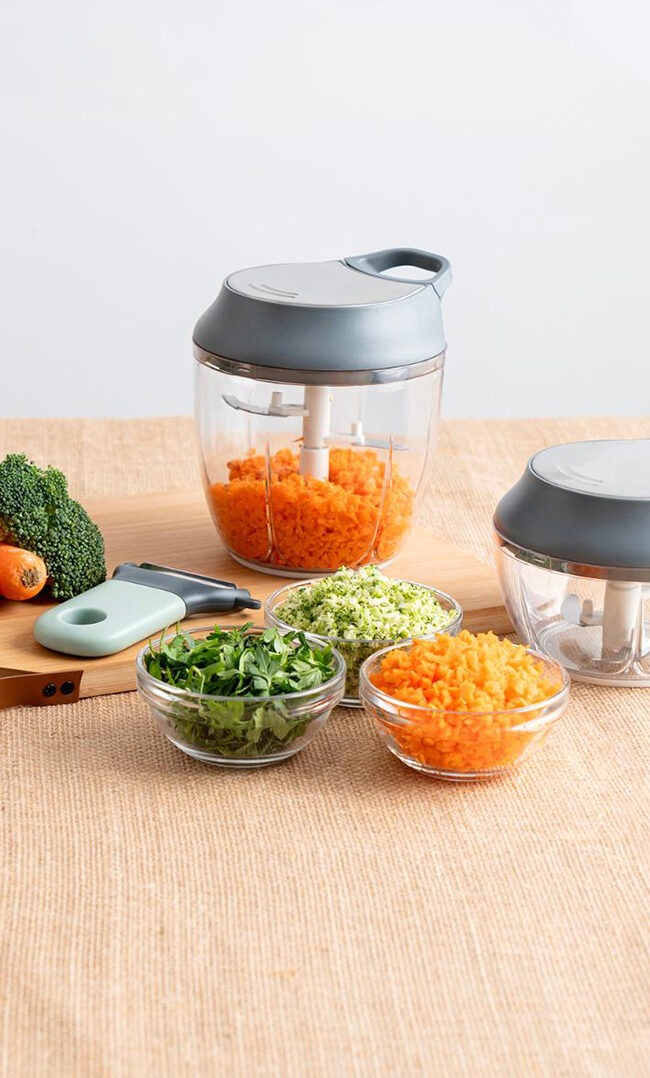 Picadora manual con verduras frescas picadas en cocina doméstica