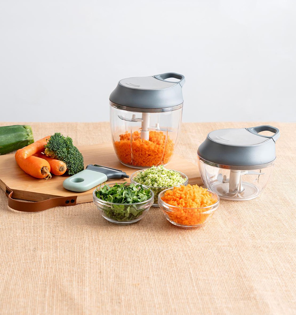 Picadora manual con verduras frescas picadas en cocina doméstica