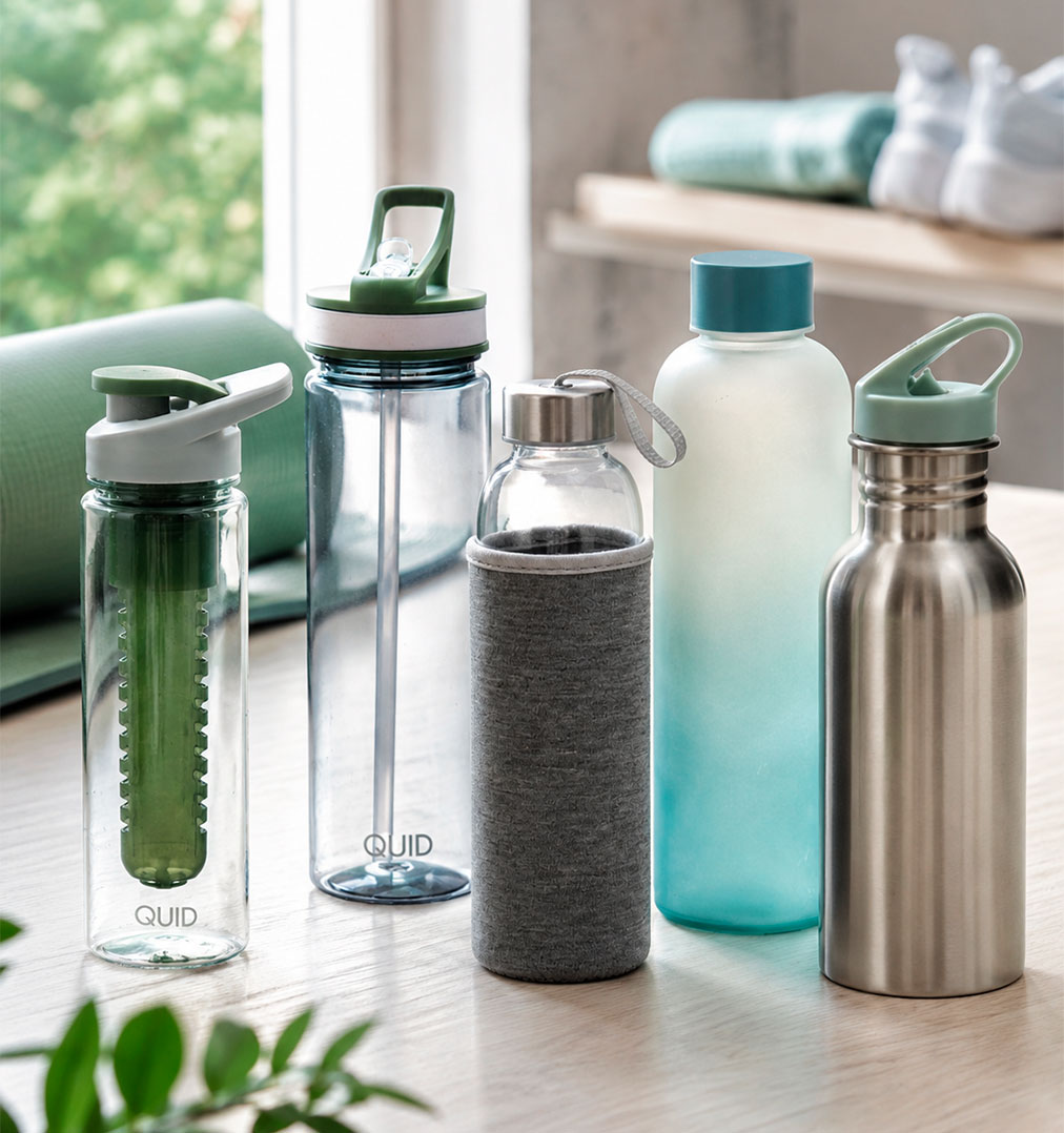 Botellas deportivas para gimnasio de vidrio plástico y acero sobre mesa con accesorios de entrenamiento