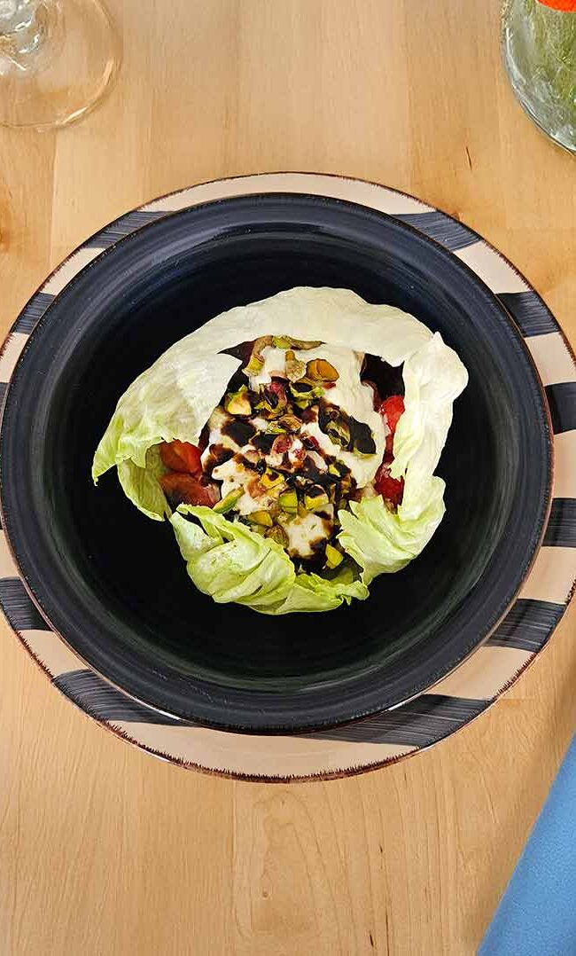 Ensalada fresca en bol de iceberg con frutas, burrata y pistachos