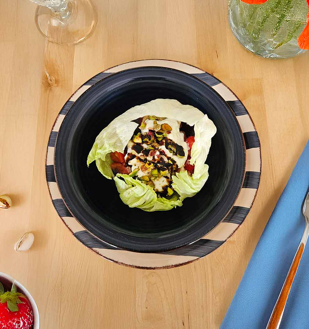 Ensalada fresca en bol de iceberg con frutas, burrata y pistachos