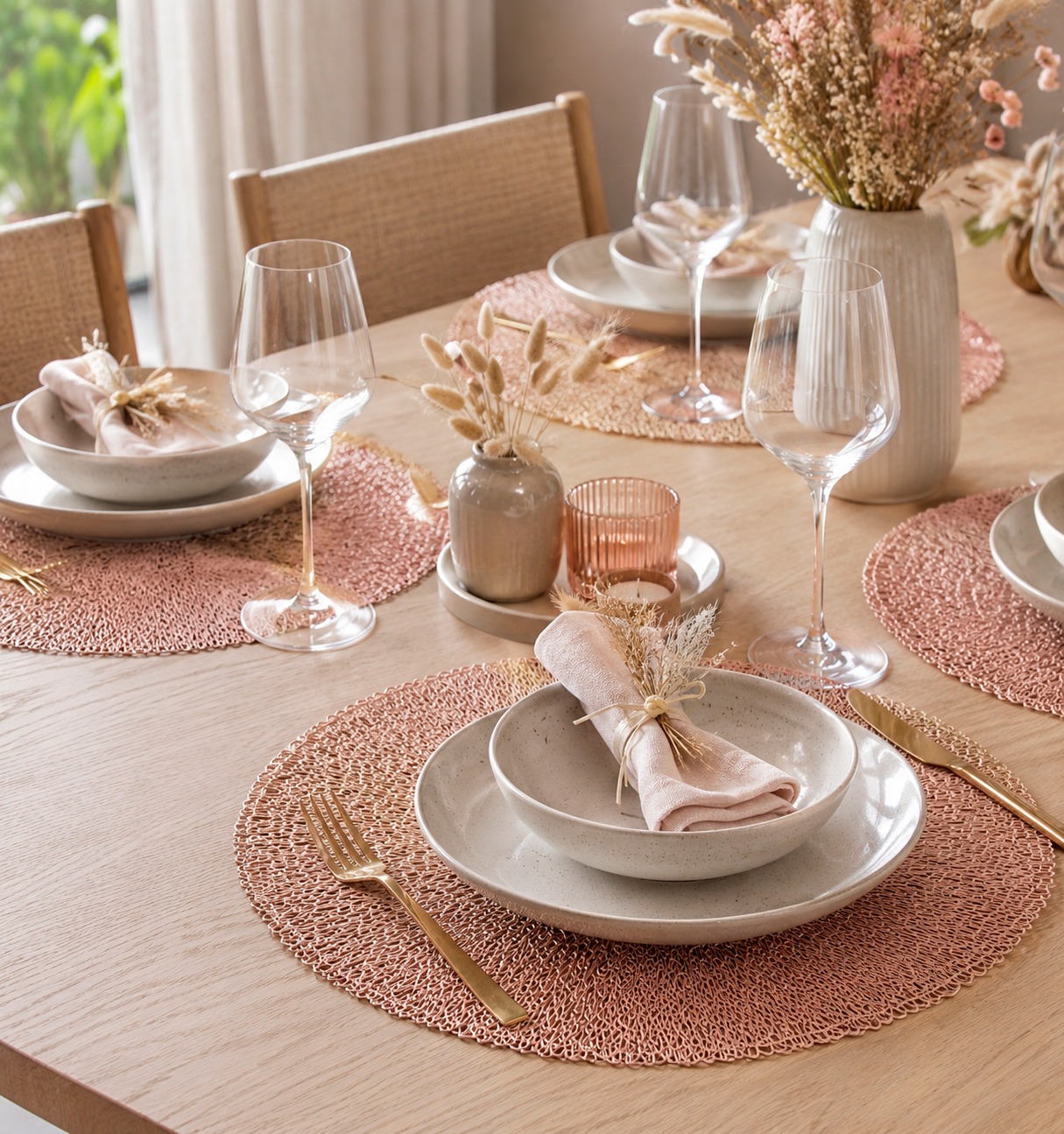 Mesa de comedor con manteles individuales redondos de rafia, vajilla blanca y vasos de cristal